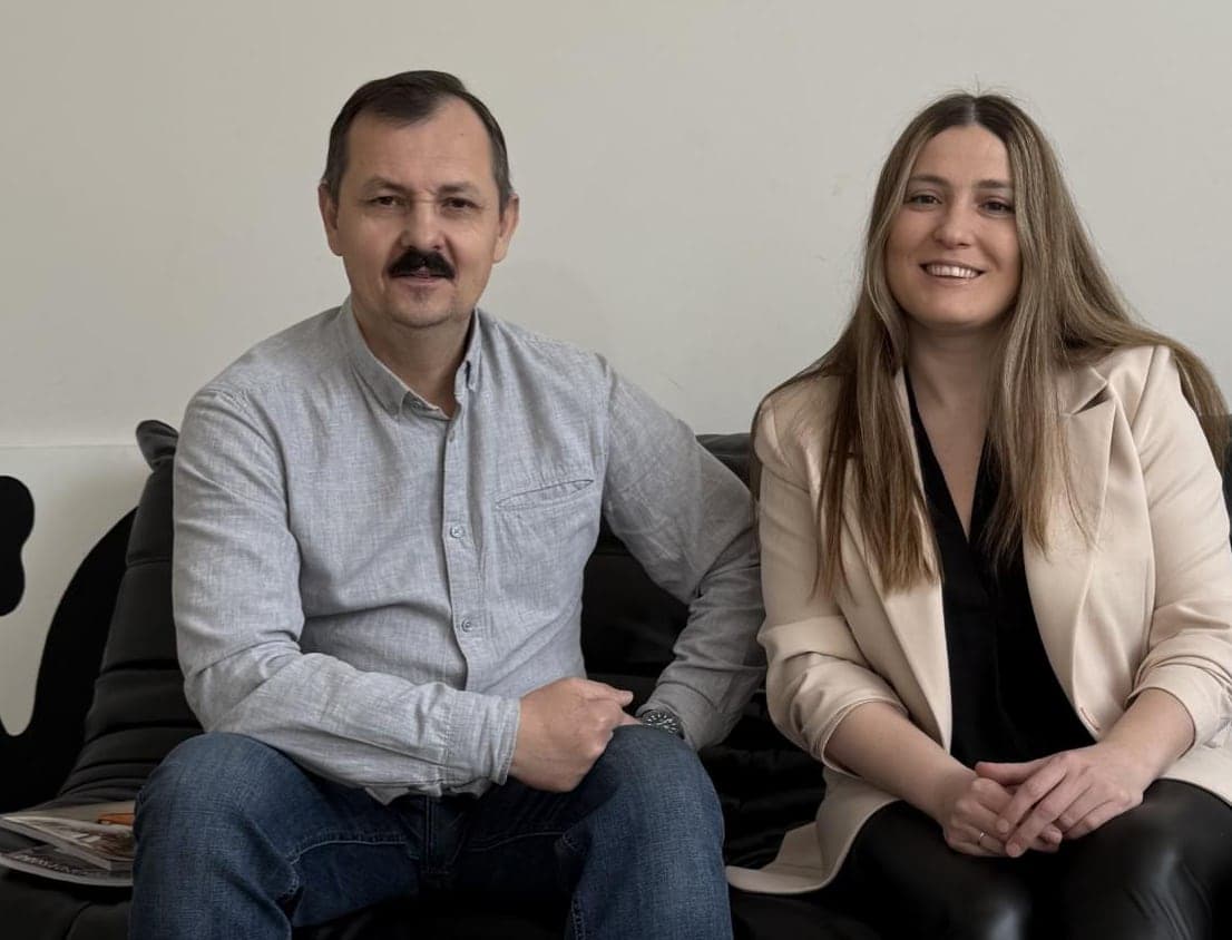 Чоловік і жінка усміхаються, сидячи поруч на дивані
